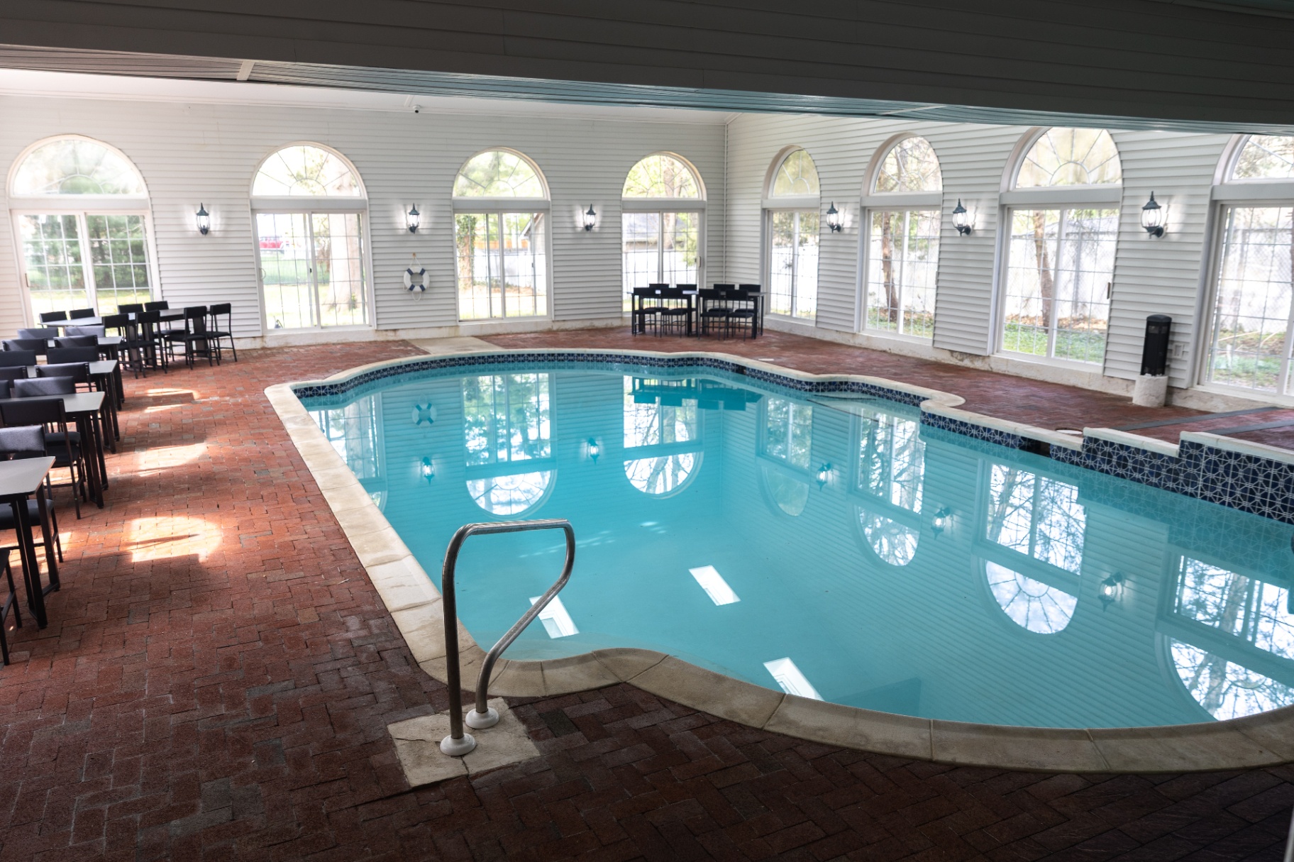 Indoor pool with brick flooring and arched glass doors